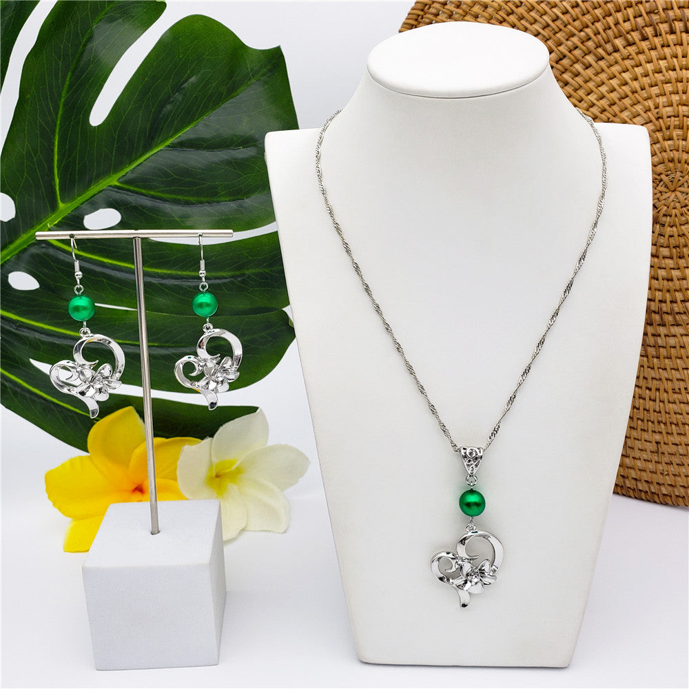 Set Of A Heart Carrying Plumeria Flower Centered With White Zircon Earrings And Necklace In Sliver & Gold Sustained With A Pearl In Different Colors